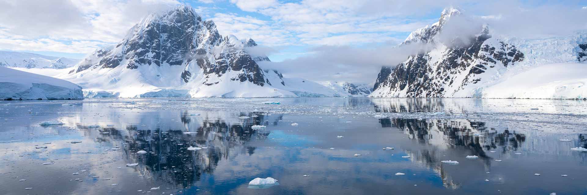 Still morning in the Lemaire Channel on an Antarctica Cruise with tall mountains and ice in the water